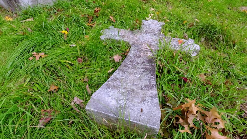 Granite cross lying flat in the grass