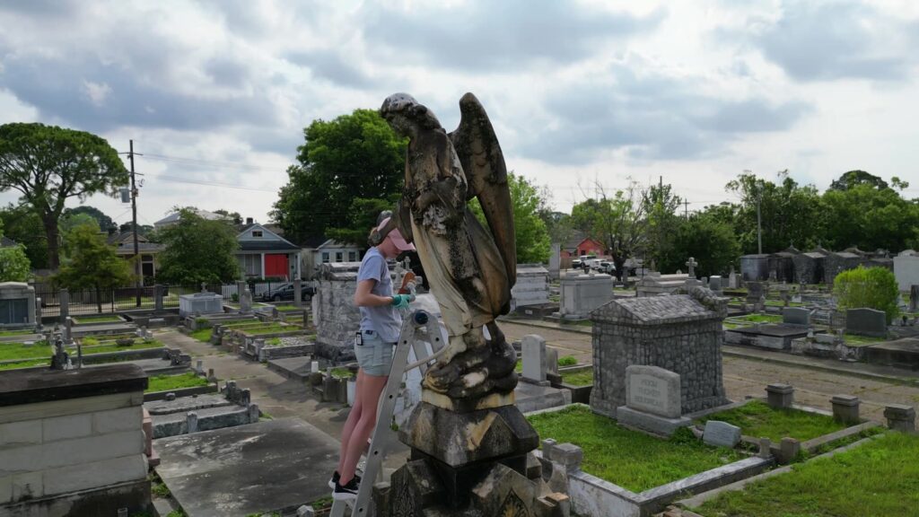 Katie DeRaddo cleaning the angel statue from a ladder